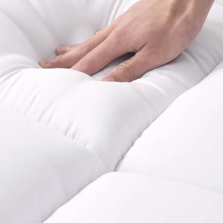 Hand pressing into the soft quilted surface of the GOPOONY mattress topper